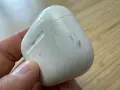 Eine schmutzige weiße Hülle für AirPods wird von einer Hand gehalten.