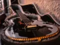 Schwarze Gitarre mit Fell ausgekleidetem Koffer.