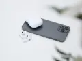 AirPods und Ladecase liegen neben einem Smartphone.