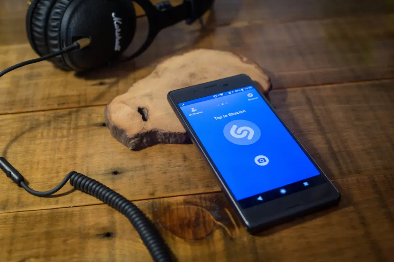 Kopfhörer und Smartphone mit Shazam-App. Wer singt dieses Lied? Shazam hilft, es herauszufinden.