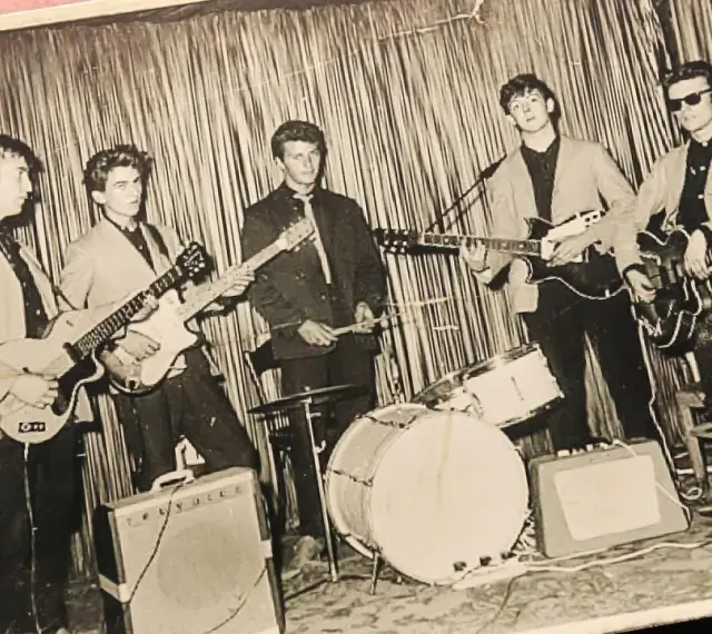 Fünf junge Männer mit Gitarren und Schlagzeug, die die Musikrichtung der 60er Jahre repräsentieren.