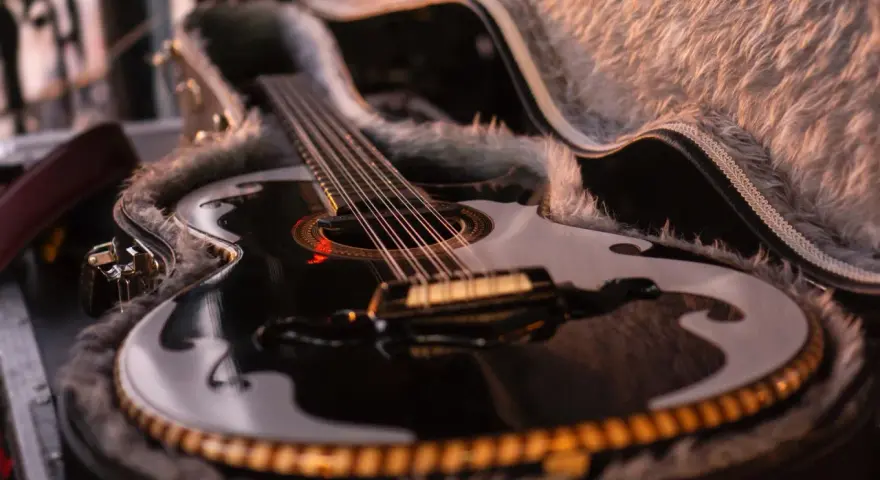 Schwarze Gitarre mit Fell ausgekleidetem Koffer.