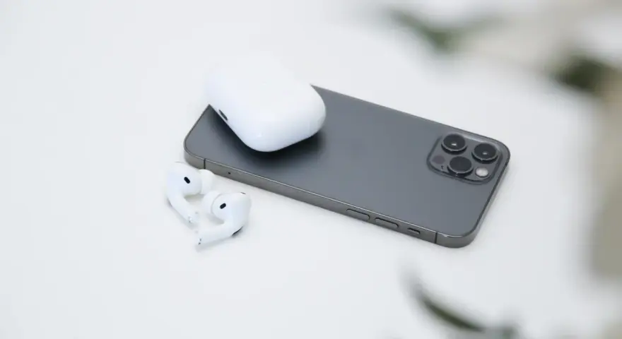 AirPods und Ladecase liegen neben einem Smartphone.