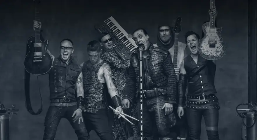 Rammstein-Bandmitglieder mit Instrumenten, schwarz-weiß.