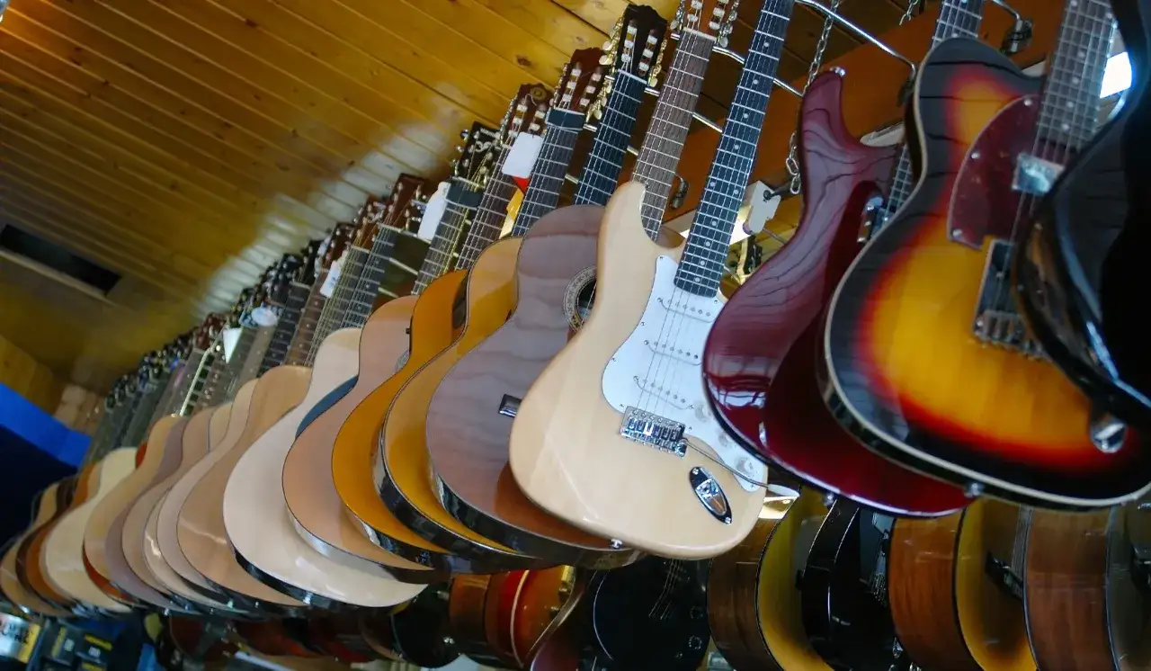 Eine Reihe von Gitarren hängt an der Wand. Wenn du eine E-Gitarre kaufen möchtest, findest du hier sicher das passende Modell.